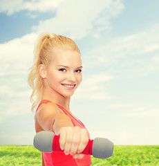 Image showing smiling beautiful sporty woman with dumbbell