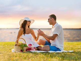 Image showing smiling couple with small red gift box on picnic