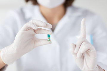 Image showing close up of scientist holding pill in lab