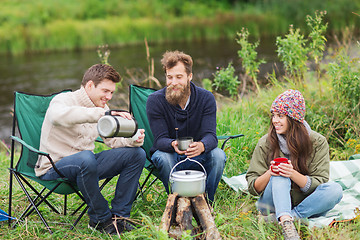Image showing group of smiling tourists cooking food in camping