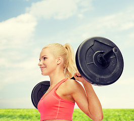 Image showing smiling sporty woman exercising with barbell