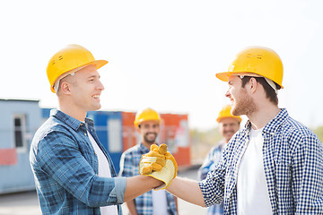 Image showing group of smiling builders in hardhats outdoors