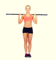 Image showing smiling sporty woman exercising with barbell