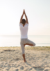 Image showing man making yoga exercises outdoors from back