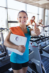 Image showing smiling woman with scales and towel in gym