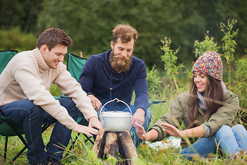 Image showing group of smiling friends cooking food outdoors