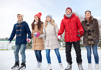 Image showing happy friends ice skating on rink outdoors