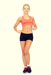 Image showing smiling sporty woman pointing at her six pack