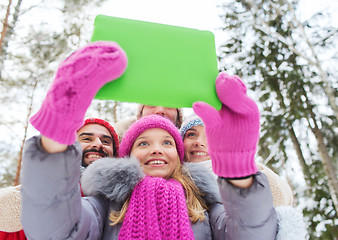 Image showing smiling friends with tablet pc in winter forest