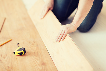 Image showing close up of male hands intalling wood flooring