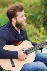Image showing smiling man playing guitar in camping