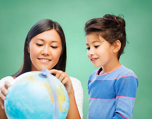 Image showing happy teacher and little school girl with globe