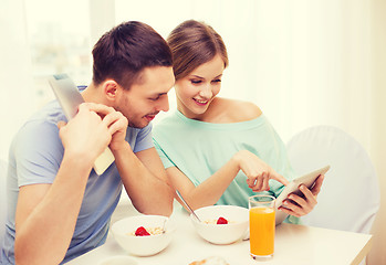 Image showing smiling couple with tablet pc reading news