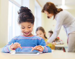 Image showing little school girl with tablet pc over classroom