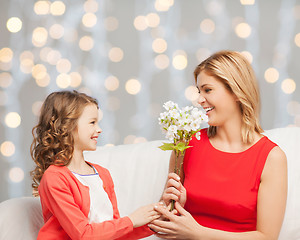 Image showing happy little daughter giving flowers to her mother