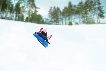 Image showing happy teenage girl sliding down on snow tube