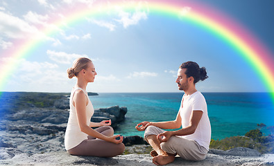 Image showing happy couple meditating in lotus pose on beach