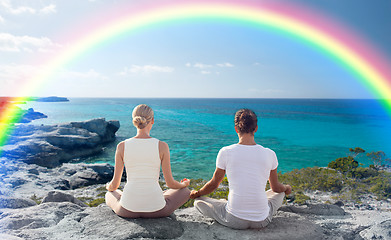 Image showing happy couple meditating in lotus pose on beach