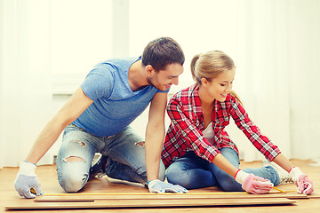 Image showing smiling couple measuring wood flooring