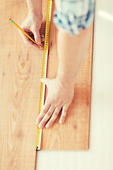 Image showing close up of male hands measuring wood flooring
