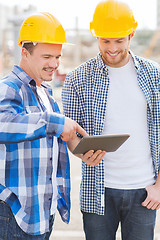 Image showing smiling builders with tablet pc outdoors