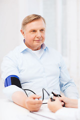 Image showing female doctor or nurse measuring blood pressure