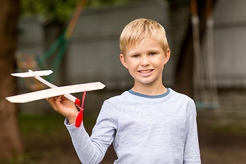 Image showing smiling little boy holding a wooden airplane model