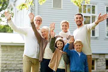 Image showing happy family waving hands in front of house