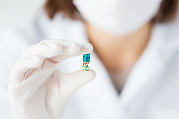 Image showing close up of scientist holding pill in lab