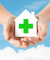 Image showing hands holding paper house with green cross