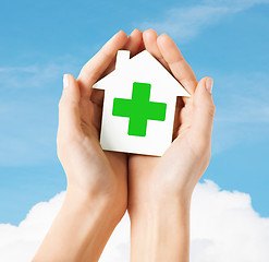 Image showing hands holding paper house with green cross