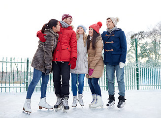 Image showing happy friends ice skating on rink outdoors