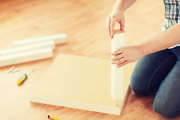 Image showing close up of male hands assemblying legs to table