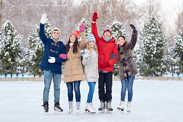 Image showing happy friends ice skating on rink outdoors