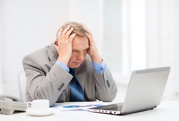 Image showing upset older businessman with laptop and telephone