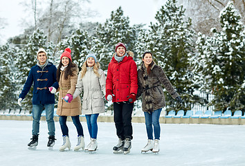 Image showing happy friends ice skating on rink outdoors