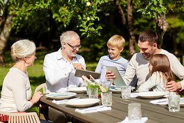 Image showing happy family with tablet pc at table in garden