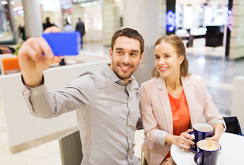 Image showing happy couple with smartphone taking selfie in mall