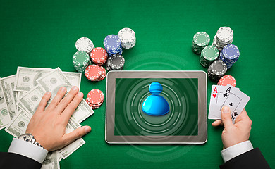 Image showing casino poker player with cards, tablet and chips