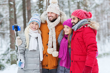 Image showing smiling friends with smartphone in winter forest