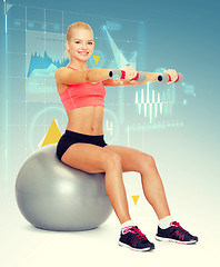 Image showing woman with dumbbells sitting on fitness ball