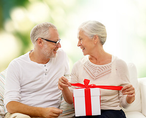 Image showing happy senior couple with gift box at home