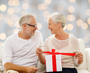 Image showing happy senior couple with gift box at home