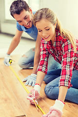 Image showing smiling couple measuring wood flooring