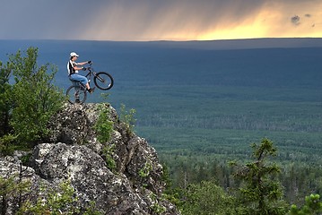 Image showing Biker with mountain bicycle stands on peak