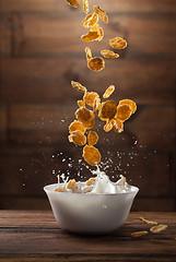 Image showing Falling corn flakes with milk splash on wood