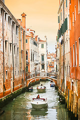 Image showing Boats sailing in water canal with orange buildings