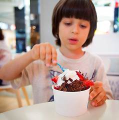 Image showing boy eating ice cream with chocolate and strawberries