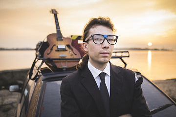 Image showing Hipter in glasses and his guitar on car rack