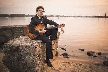 Image showing Male musician and his guitar on shore